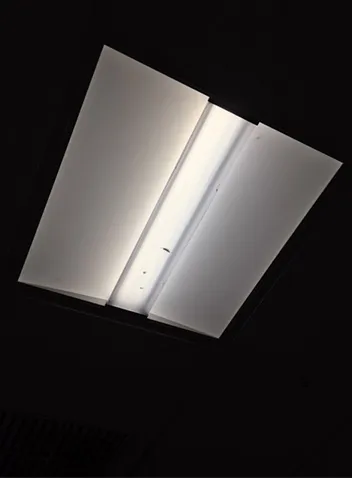 The same troffer photographed unlit against black, so the shape of the reflectors and the way they fold around the lamp can be seen.