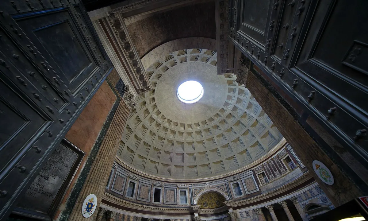 Looking straight up inside the Pantheon at the coffered concrete dome, its sunken panels rising in rings to the open oculus at the top, which reads as a small brilliant disc of daylight.
