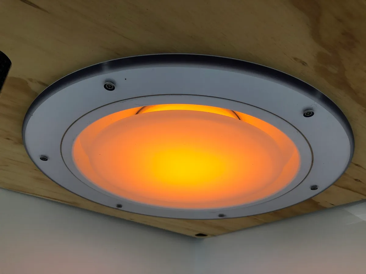 The same Salvalux fitting lit warm amber instead of white, showing the colour change the luminaire can make in a patient room.